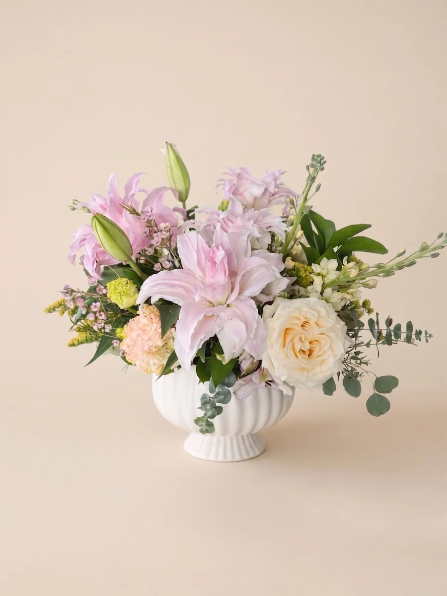 The Arabella - pink double lilies and cream garden rose with eucalyptus in a white scalloped vase
